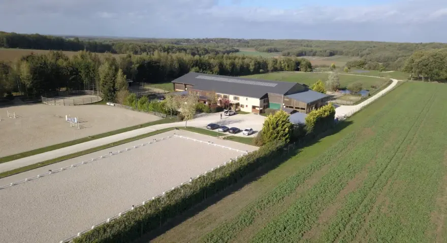 Vue aérienne d'une écurie avec manège et carrière de dressage. Le système de **carrière subirrigation** assure un sol parfait pour les chevaux.