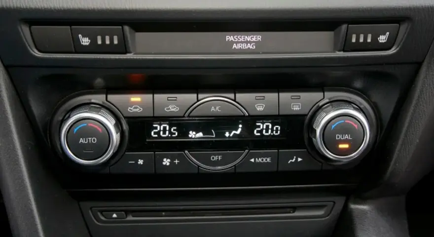 Panel sterowania klimatyzacją w samochodzie, z pokrętłami AUTO i DUAL, wyświetlaczem temperatury 20.5°C i ikonami nawiewu. Idealny do ozonowania klimatyzacji.