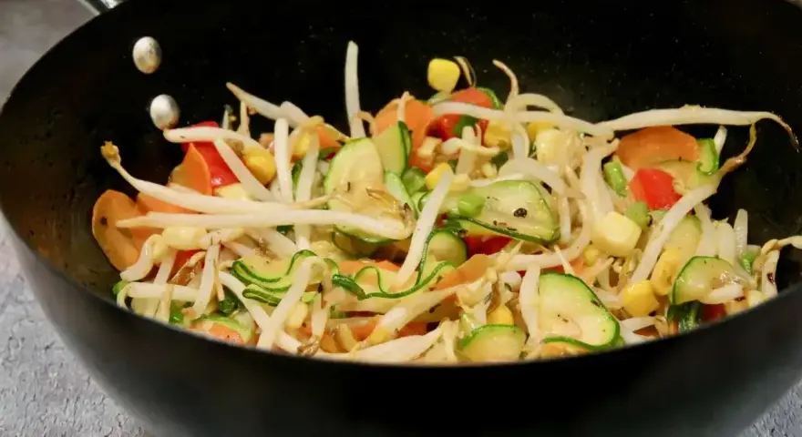 Kolorowe warzywa teriyaki w woku: kiełki fasoli mung, cukinia, marchewka, papryka i kukurydza.