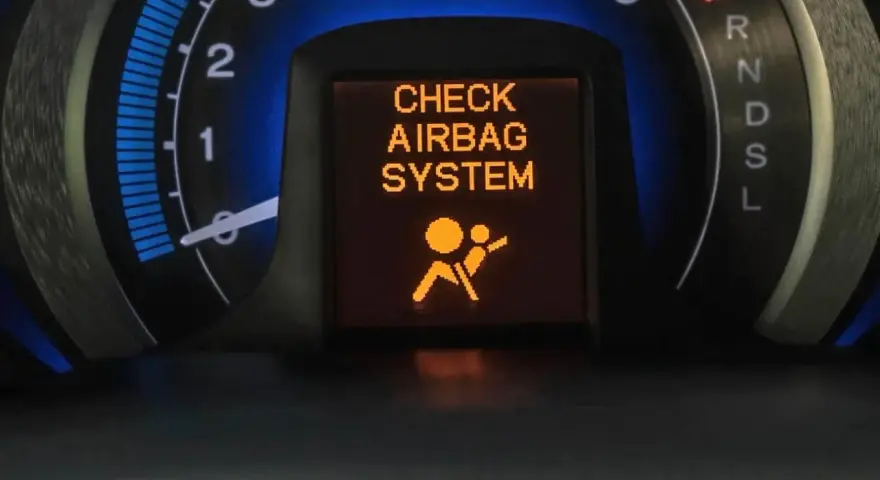 Na desce rozdzielczej świeci się pomarańczowa kontrolka poduszki powietrznej z napisem "CHECK AIRBAG SYSTEM" i ikoną pasażera.