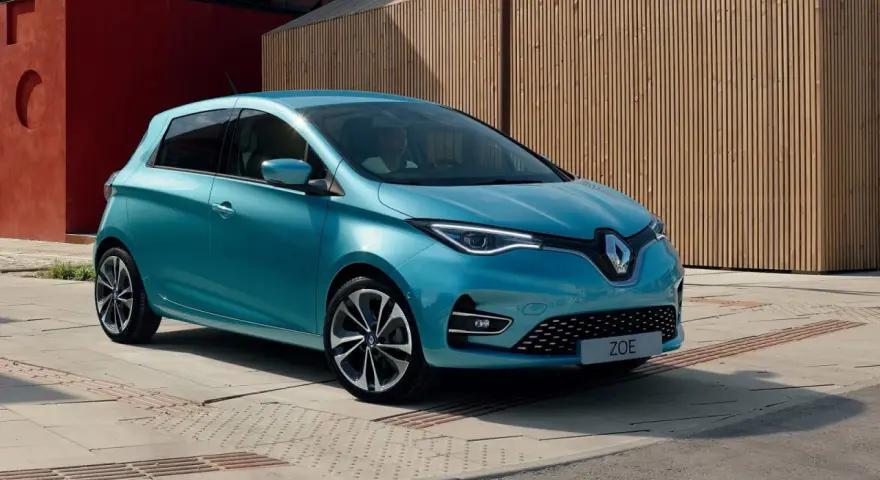 Błękitny Renault Zoe z nowoczesnymi światłami LED stoi na tle drewnianej elewacji.
