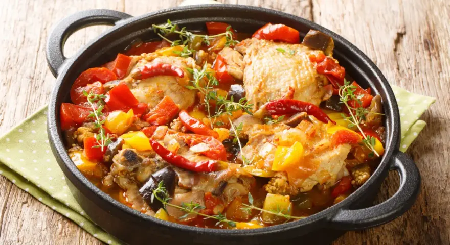 Sobracosce di pollo stufate con peperoni, pomodori, melanzane e peperoncino, guarnite con timo fresco.