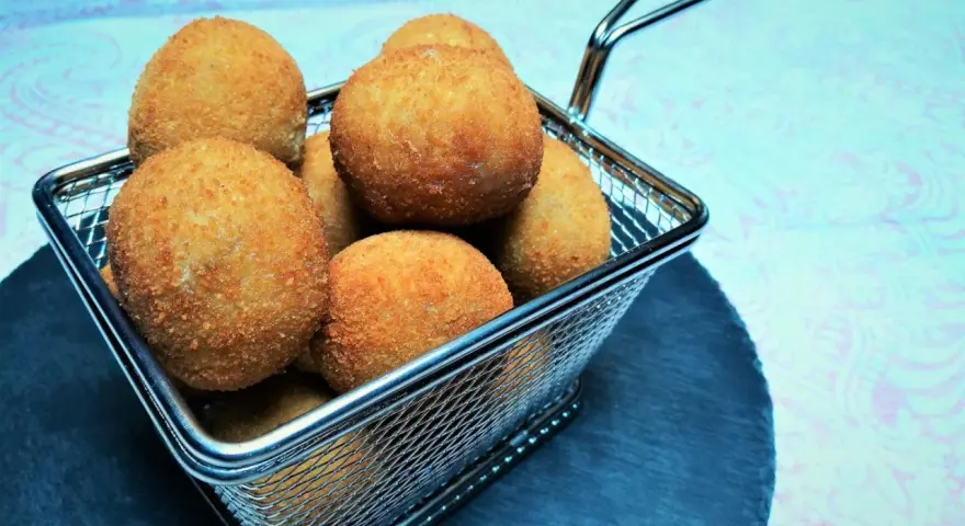 Croquetas doradas y crujientes en una cesta metálica.