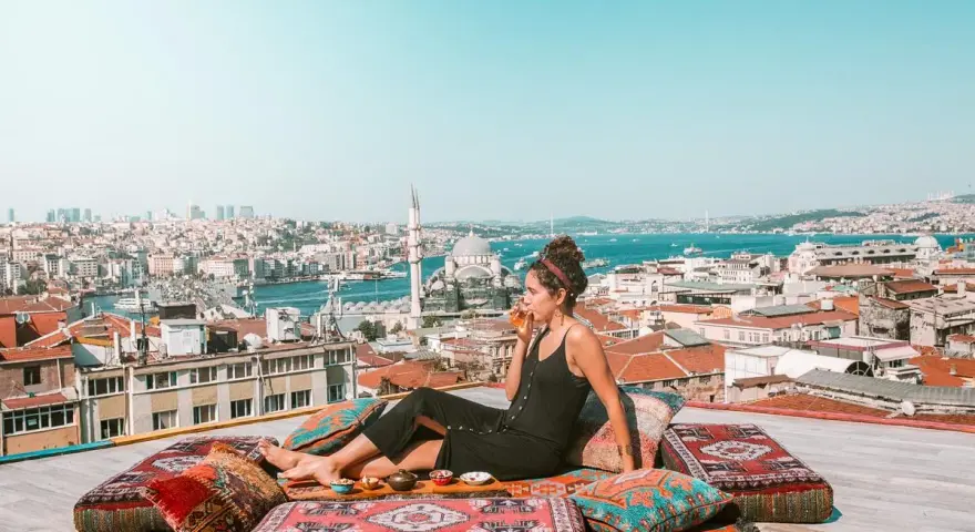 A woman enjoys a drink on a rooftop overlooking Istanbul, a scene straight out of a Rick Steves Turkey adventure.