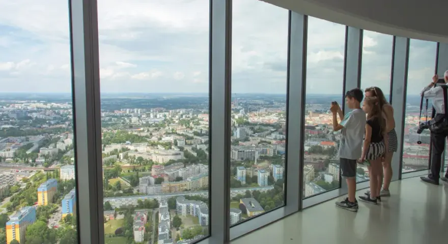 Widok z tarasu widokowego Sky Tower. Rodzina podziwia panoramę miasta, doceniając jego ogromną wysokość.
