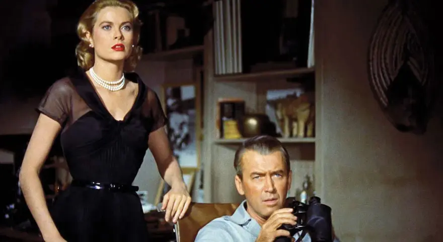 Grace Kelly e James Stewart in una scena di un film thriller suspense. Lui osserva con il binocolo, lei elegante in abito nero.