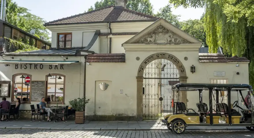 Kazimierz, Kraków. Bistro Bar i zabytkowa brama z hebrajskimi napisami. Obok żółty meleks, idealny na zwiedzanie.