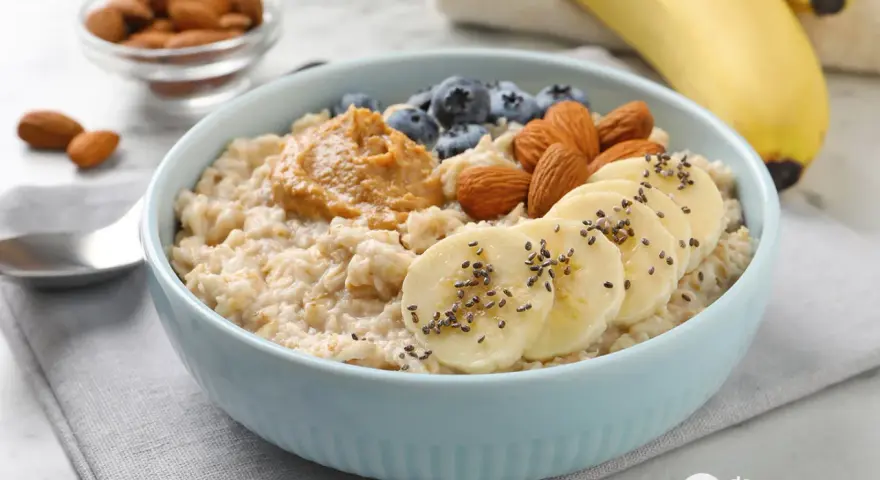 Avena cremosa con plátano, arándanos, almendras y mantequilla de maní. Una guía visual de como cocinar avena para un desayuno nutritivo.