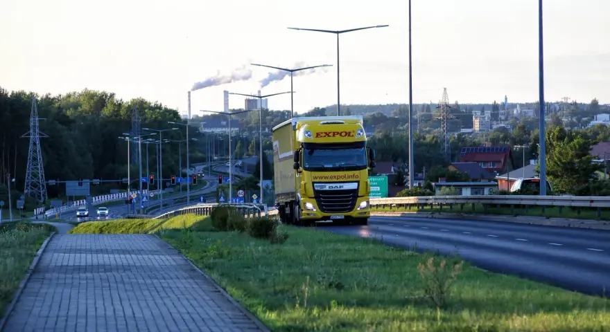Żółta ciężarówka EXPOL jedzie drogą, symbolizując mobilność i wyzwania związane z pakietem mobilności a umową zlecenie.