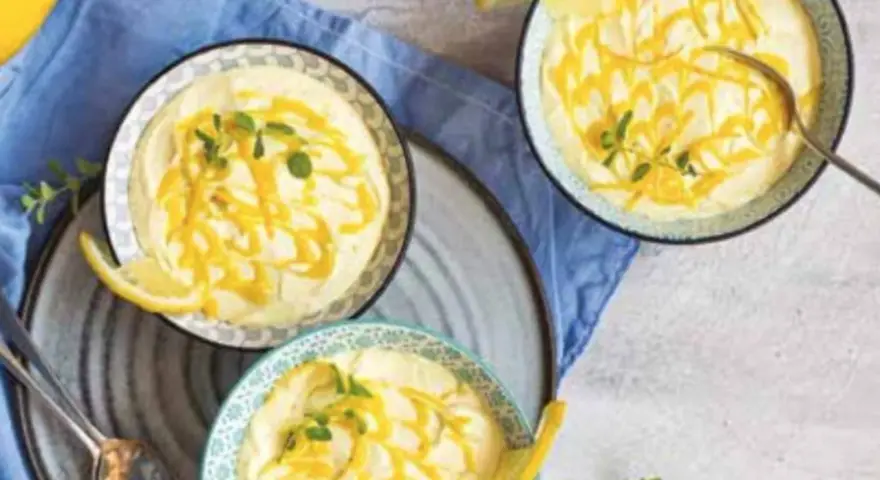 Tre coppette di deliziosa mousse al limone, guarnite con scorza di limone e menta fresca.