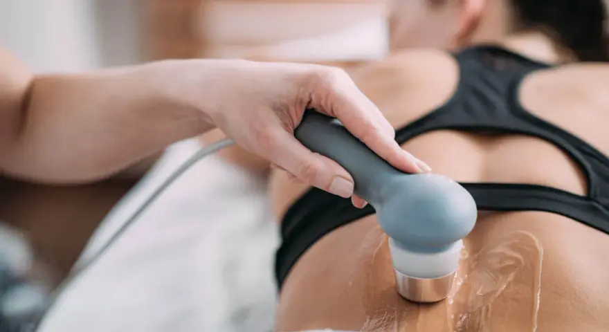 Therapeutin führt Ultraschall Physiotherapie am Rücken einer Patientin durch. Gel auf der Haut für die Behandlung.