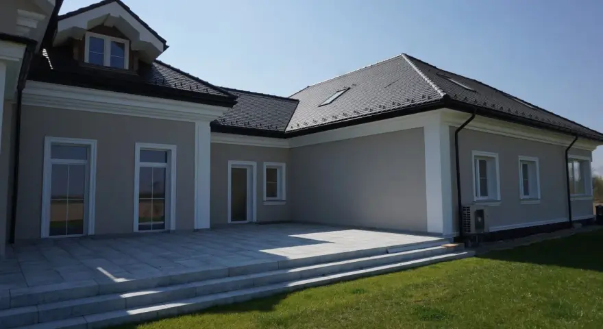 Nowoczesny dom z tarasem i trawnikiem. Elegancki gzyms podkreśla architekturę budynku.