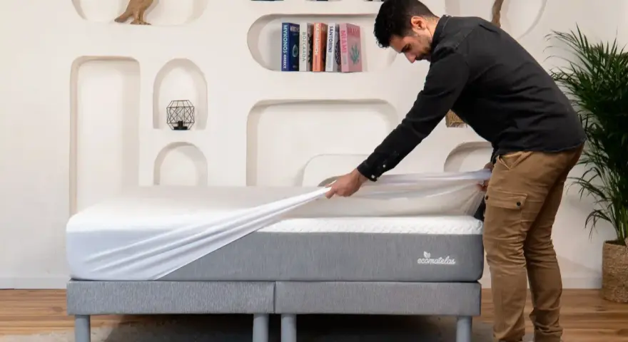 Un homme installe une housse sur un matelas, assurant ainsi sa protection.
