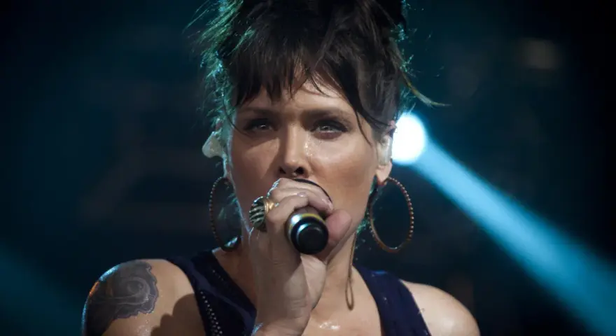 Beth Hart z tatuażem na ramieniu, w okrągłych kolczykach, śpiewa do mikrofonu. Choć nie widać jej dzieci, jej energia na scenie jest jak dla nich.