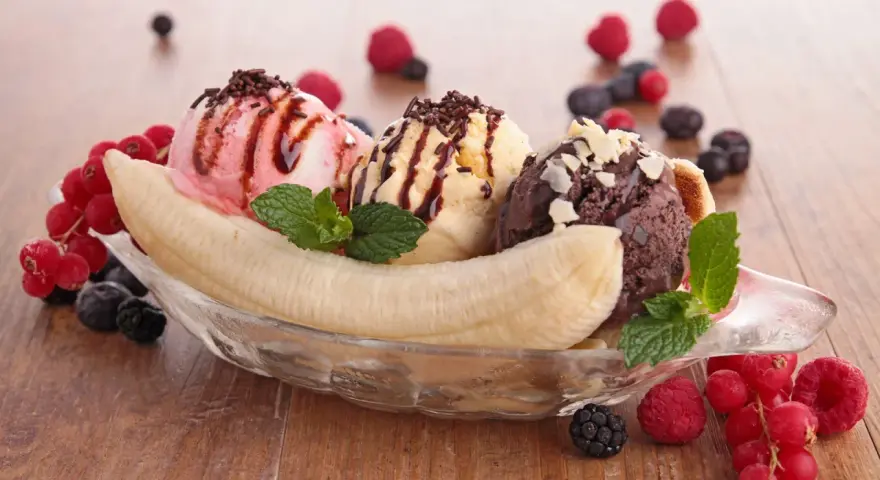Ein klassisches Banana Split Eis mit drei Kugeln Eis, garniert mit Beeren und Schokostreuseln.