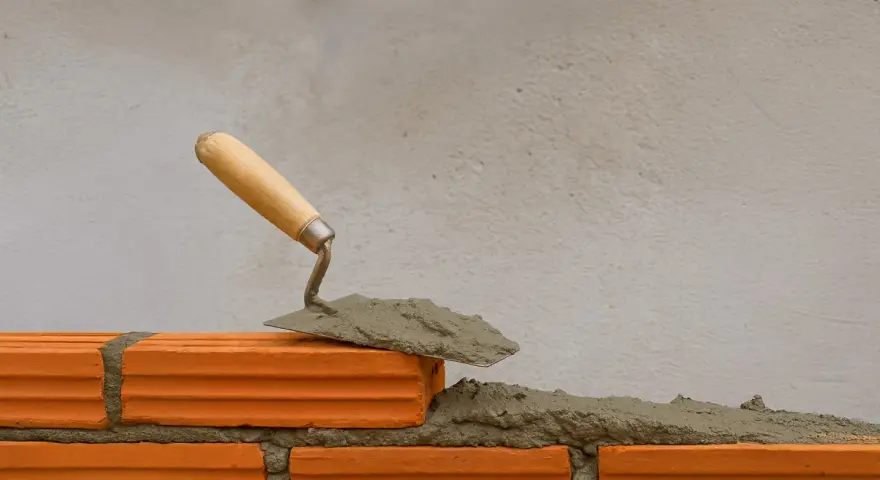 Una cazzuola con la malta pronta per costruire un muro. La malta a cosa serve? A tenere insieme i mattoni, creando strutture solide.