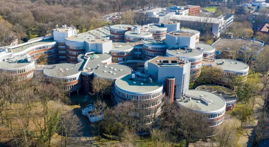 Einzigartige Architektur auf dem **Campus Duisburg**. Runde Gebäude mit vielen Fenstern gruppieren sich zu einem futuristischen Komplex inmitten von Bäumen.