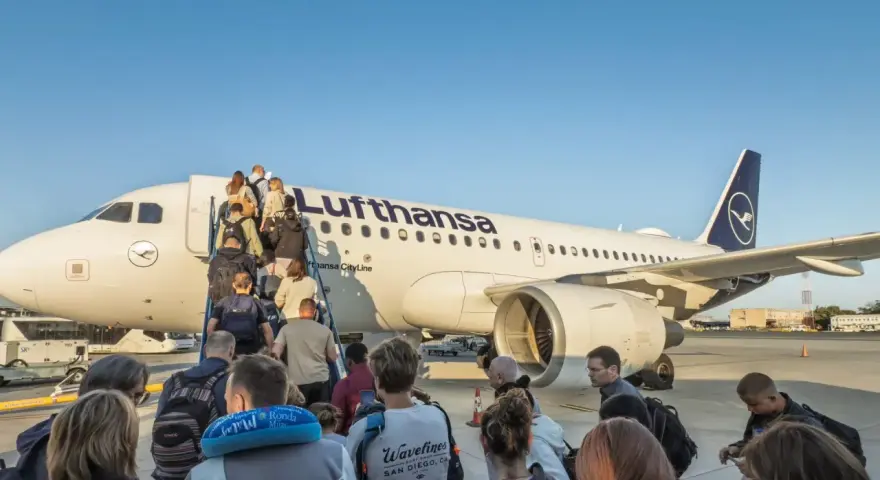 Pasażerowie wsiadają po schodkach do samolotu Lufthansa.