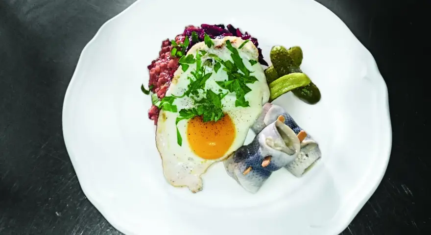 Labskaus mit Spiegelei, Rollmops und Gewürzgurken. Die Herkunft dieses norddeutschen Gerichts ist Seefahrer-Tradition.