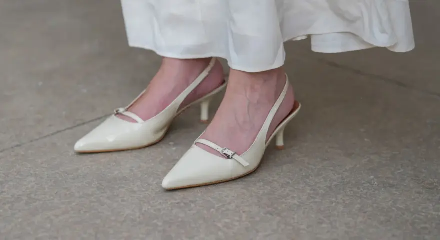 Eleganckie, kremowe szpilki z paskiem na pięcie, idealne do letnich sukienek. Niewidoczne skarpetki do szpilek zapewniają komfort.