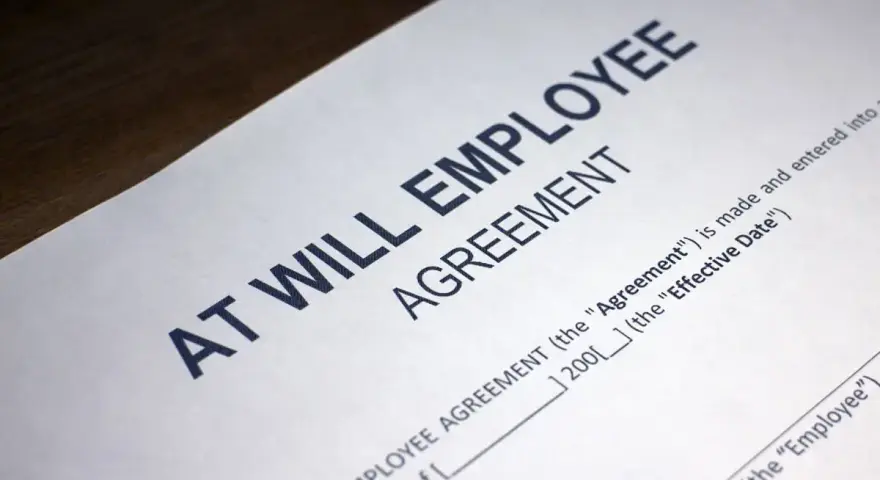 Close-up of an "At Will Employee Agreement" document, illustrating what does at-will employment mean: either party can terminate the relationship at any time.