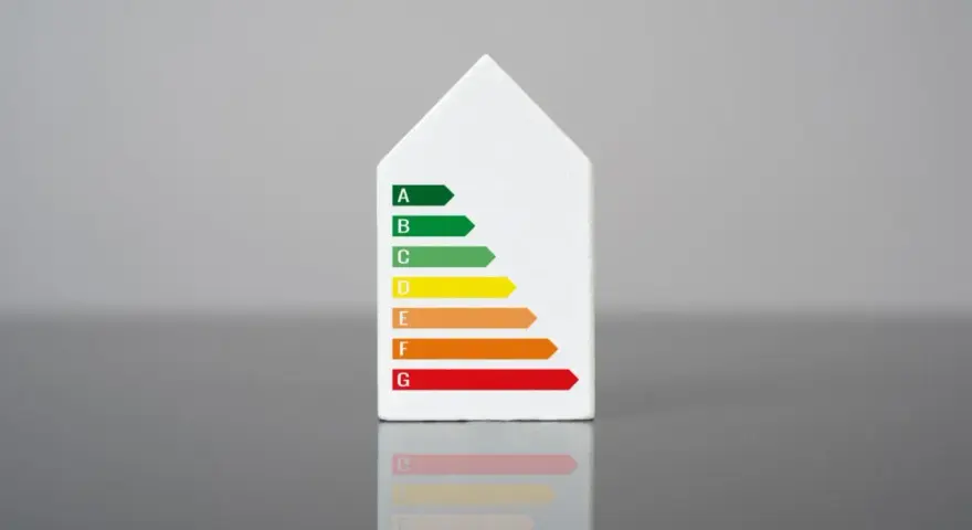 Biały model domu z naklejką klasy energetycznej. Świadectwo energetyczne mieszkania ocenia jego efektywność.