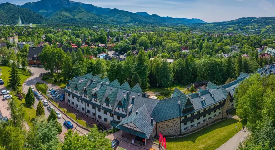 Widok z lotu ptaka na hotel Antałówka w Zakopanem, otoczony zielenią i górami w tle.