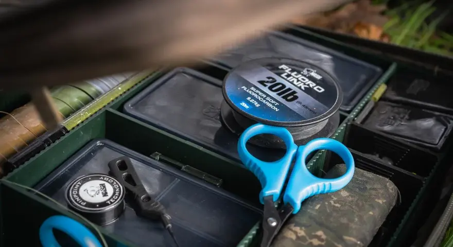 Alles für die beste Karpfenmontage: Fluorocarbon-Schnur, Schere und Zubehör in einer Tacklebox.