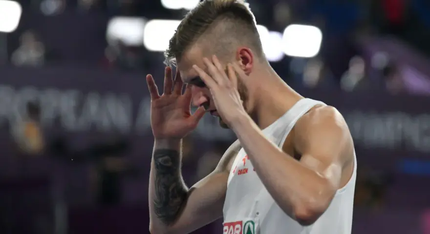 Norbert Kobielski, lekkoatleta, zamyka oczy, skupiając się przed ważnym startem.
