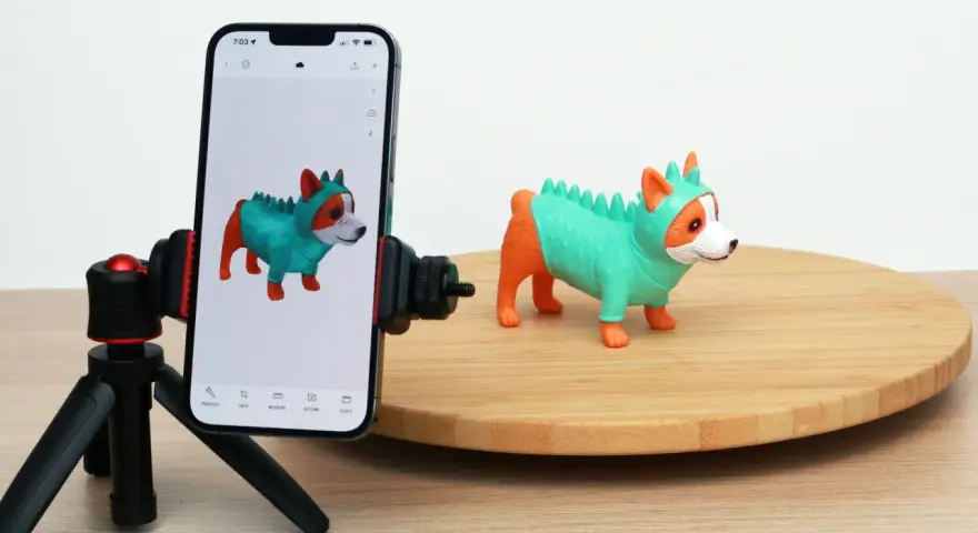 A phone on a tripod captures a toy dog, demonstrating 3D scanning for 3D printing.