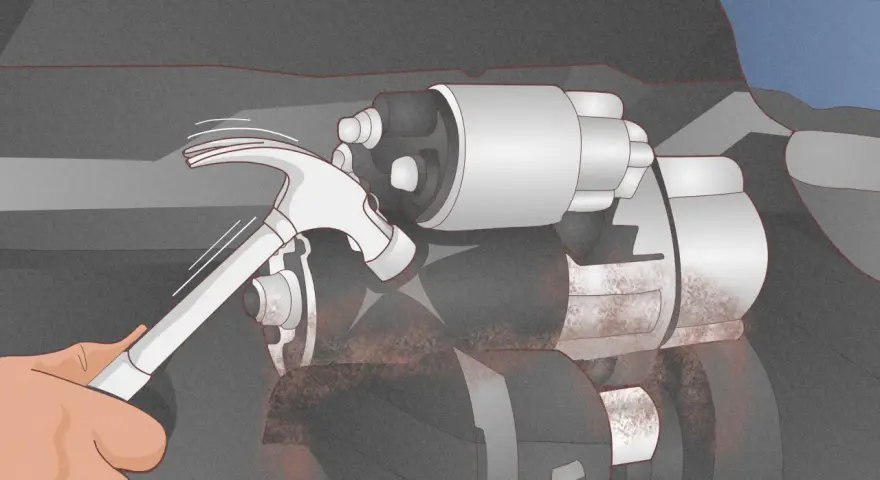 A hand uses a hammer to tap a car's starter motor, a common trick for how to start a car with a bad starter.