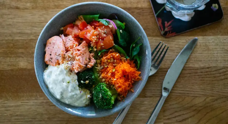 En härlig poke bowl med lax, broccoli, tomat, rivna morötter och en krämig sås. Perfekt för en hälsosam lunch.