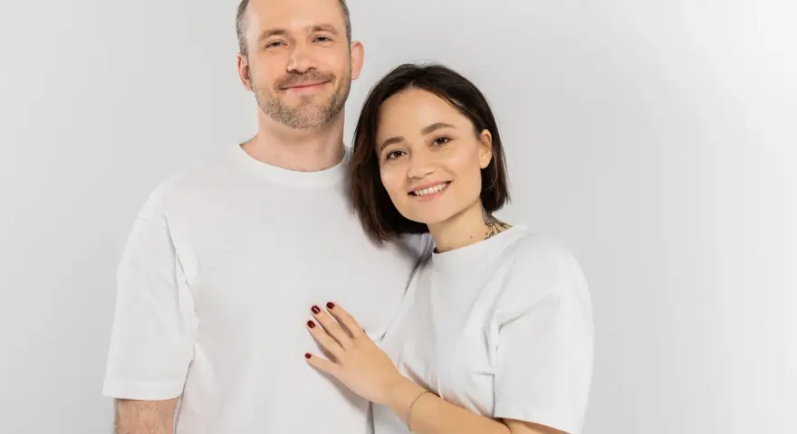 Uśmiechnięta para, on z zarostem, ona z tatuażem na szyi. Idealni do rozmowy o pytania na randkę.