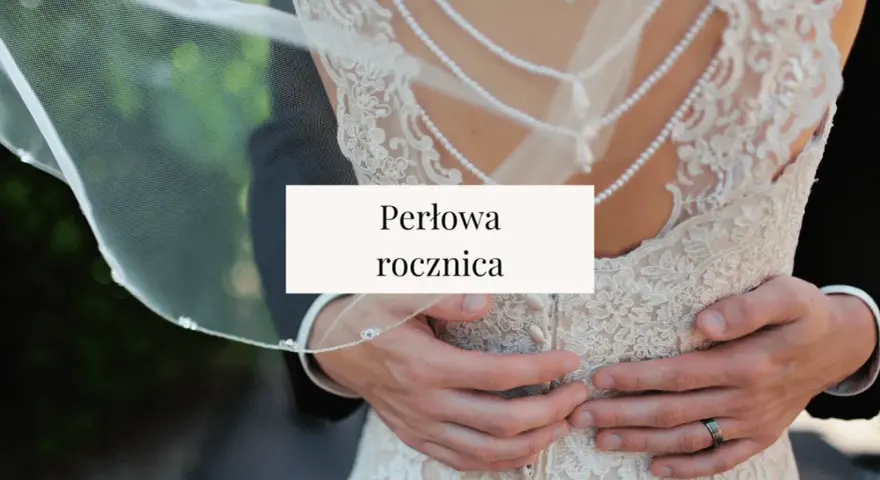 Perłowa rocznica ślubu. Dłonie obejmujące suknię ślubną z koronki i pereł.