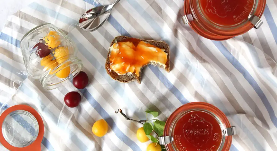 Kriecherl-Marmelade auf Brot, Gläser und frische Früchte. Perfekt für leckere Kriecherl Rezepte.