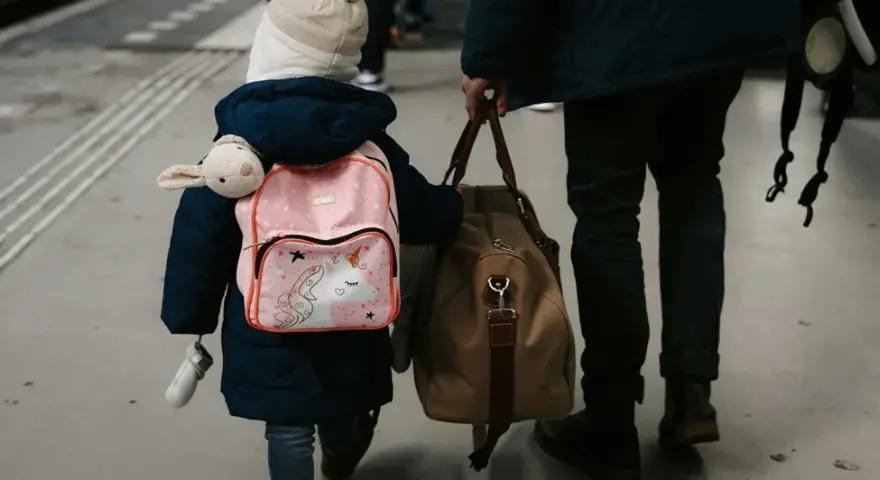 Enfant avec sac à dos licorne et doudou, accompagnant un adulte. Voyage pour une autorisation de sortie de territoire mineur parents séparés.