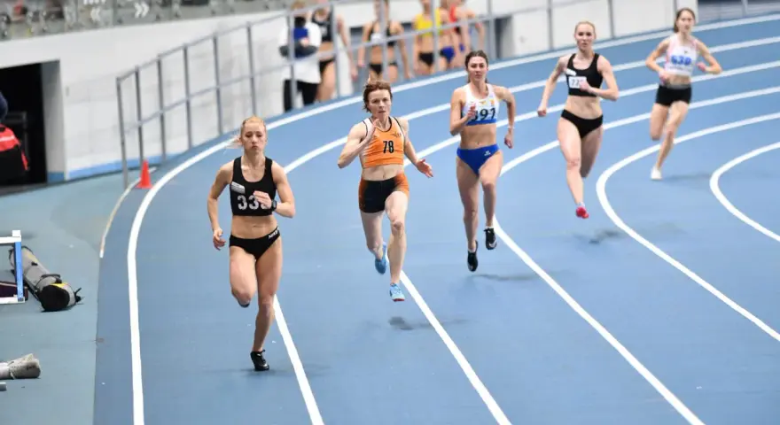 Aneta Lemiesz biegnie w zawodach lekkoatletycznych, walcząc o zwycięstwo na bieżni.
