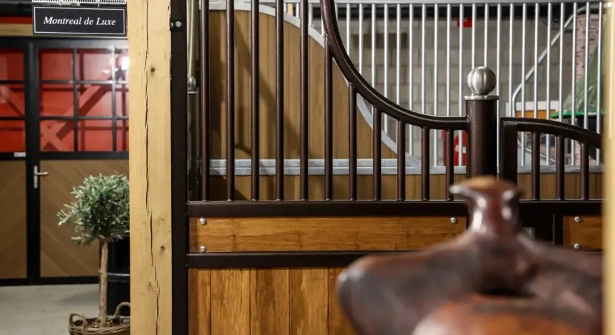Une écurie de luxe avec des portes en bois, des barreaux en métal et un signe "Montreal de Luxe".