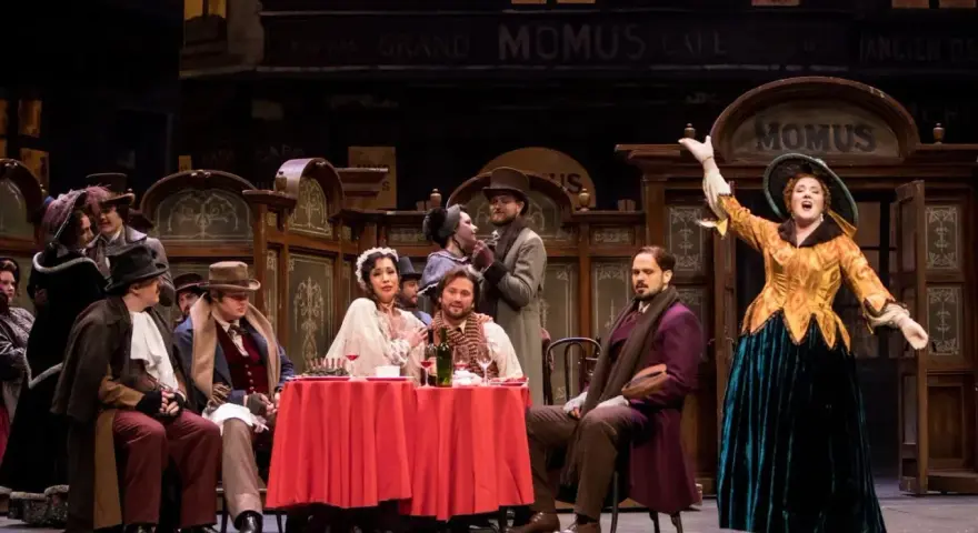 Scena z operetki. Kobieta w żółtej sukni śpiewa na tle kawiarni "Momus".