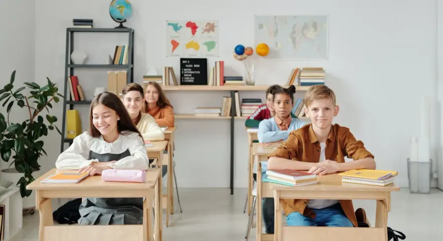 Uczniowie siedzą w ławkach w klasie, która wygląda jak szkoła średnia w Niemczech.