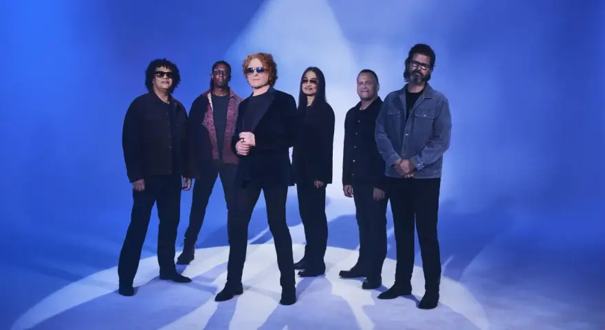 Zespół Simply Red gotowy na koncert w Polsce. Sześciu muzyków pozuje na tle niebieskiego światła.