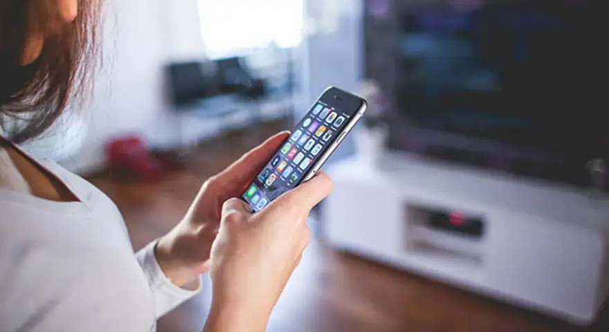 Kobieta trzyma w dłoniach iPhone A1586, przeglądając aplikacje.