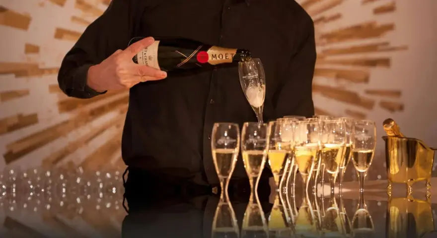 Kelner nalewa szampan Moët & Chandon do kieliszków, przygotowując się do wesela.