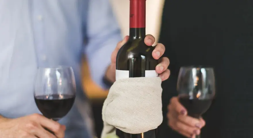 Para świętuje, trzymając butelkę wina. Pamiętaj, wino im starsze tym lepsze.