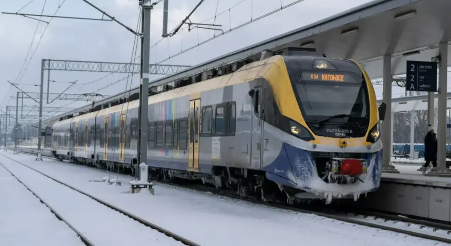 Pociąg EN78A-008 B relacji R34 Katowice stoi na zaśnieżonym peronie. Podróżuj taniej z bliskimi, wybierając kolej.