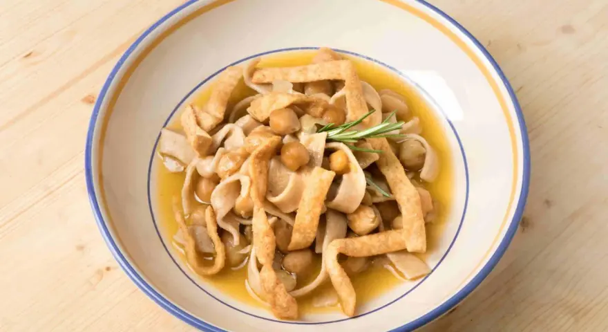 Piatto di ciceri e tria, pasta fresca con ceci e croccanti straccetti fritti, guarnito con rosmarino.