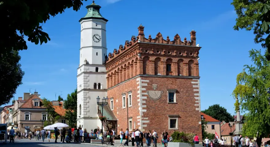 Ratusz w Sandomierzu z zegarem i zegarem słonecznym. Spacerujący ludzie na rynku, ciekawe miejsca Sandomierza.