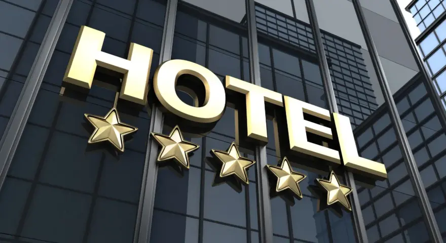 Złote litery "HOTEL" i pięć gwiazdek na nowoczesnym budynku. Spełnia hotel 4 gwiazdki wymagania luksusu i komfortu.