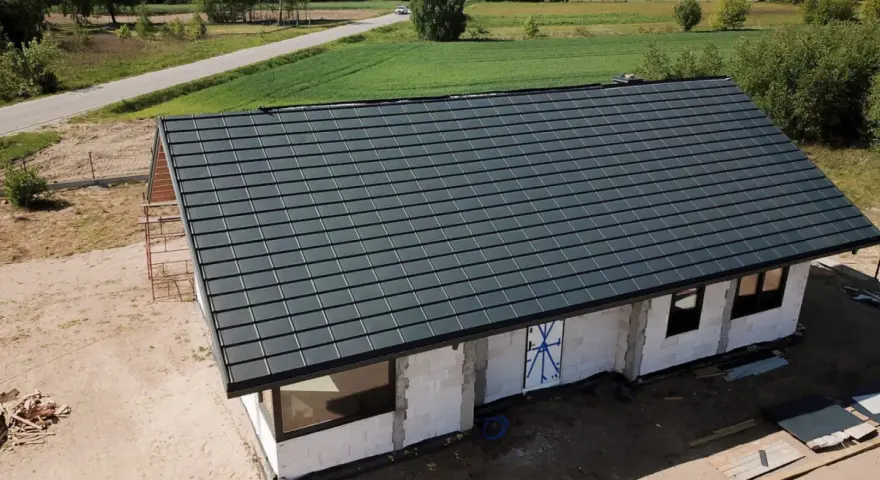 Nowy dom w budowie z ciemnoszarym dachem, widok z góry.