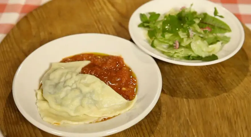 Ein Teller mit Maultaschen in Tomatensoße und ein kleiner Salat. Perfekt für ein schnelles Maultaschen Rezept.